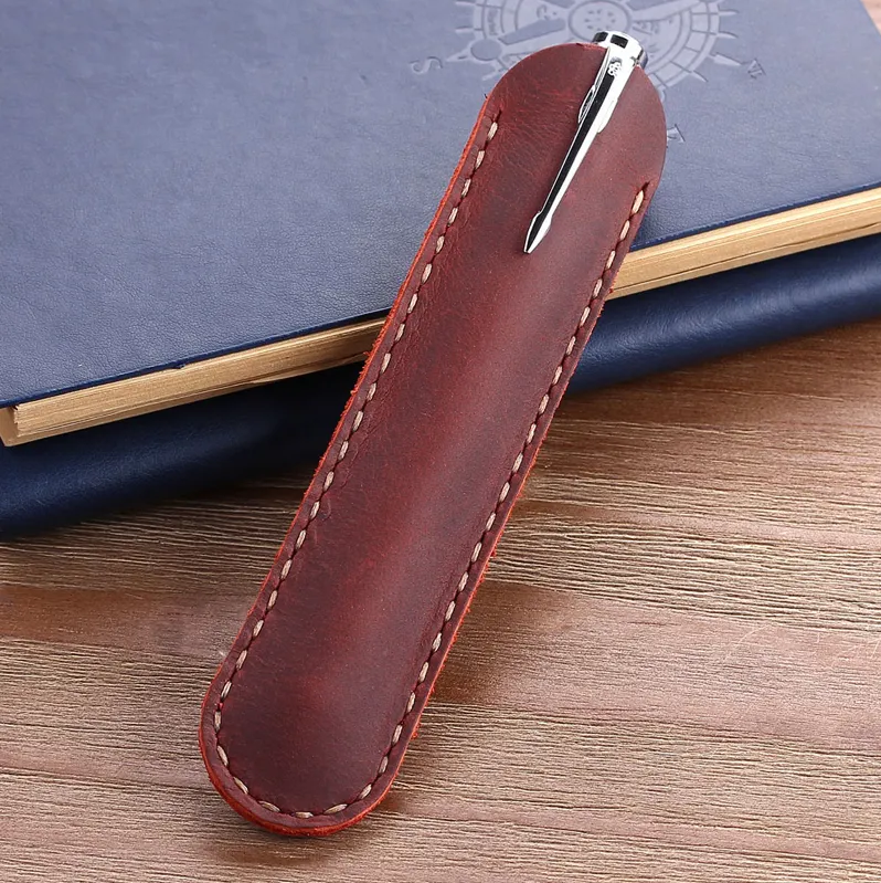 Hand-stitched Italian distressed leather pen sleeve in red, shown on a journal with a wood background – rustic single pen holder