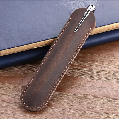 Brown leather pen holder with a pen on a wooden surface